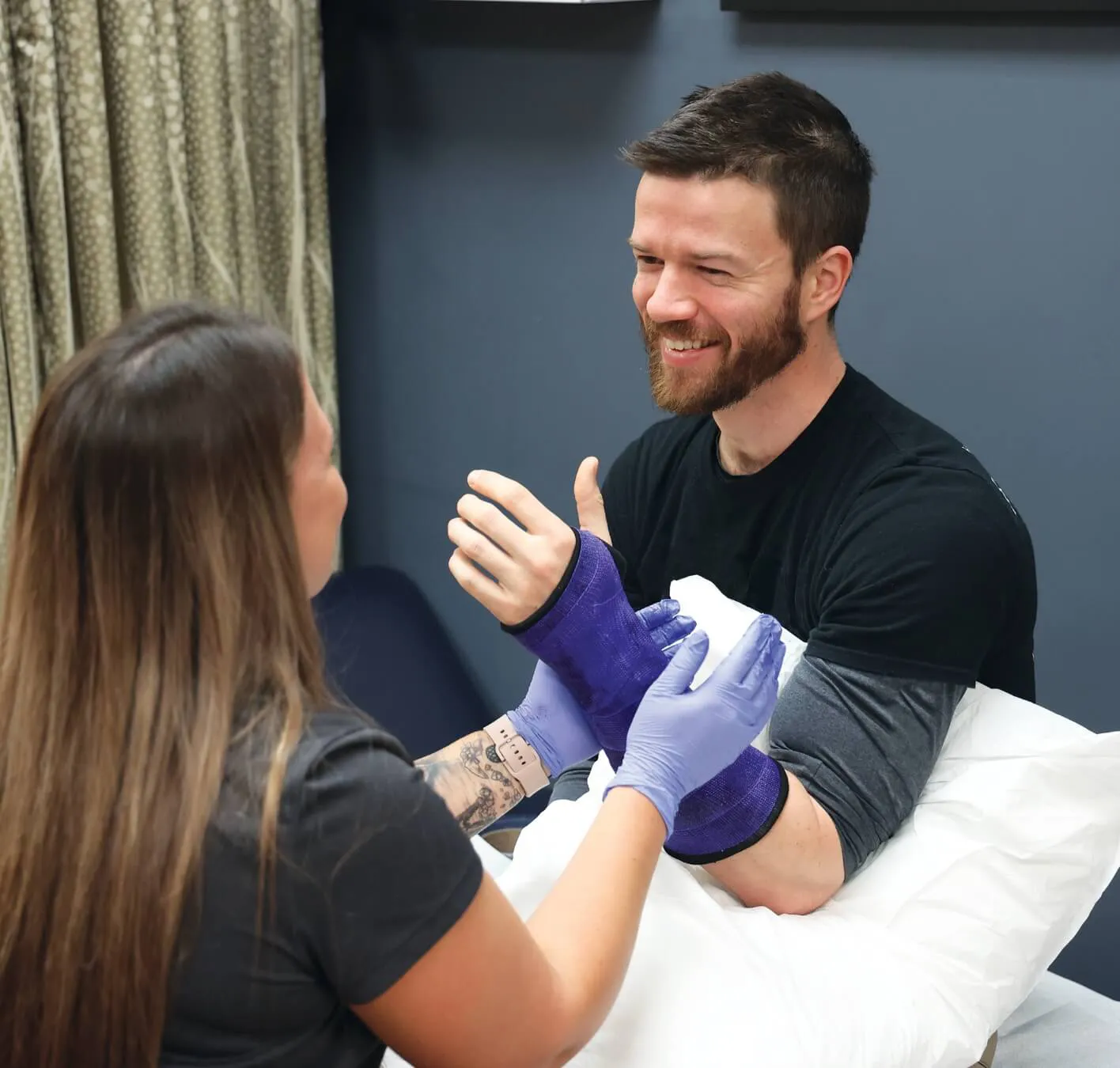 man with purple splint being helped by nurse practitioner